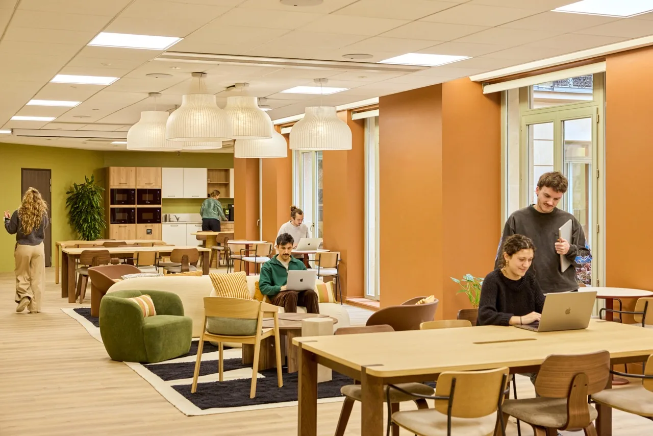 Morning coworking open space in Paris, with shared tables, armchairs and coworkers at work