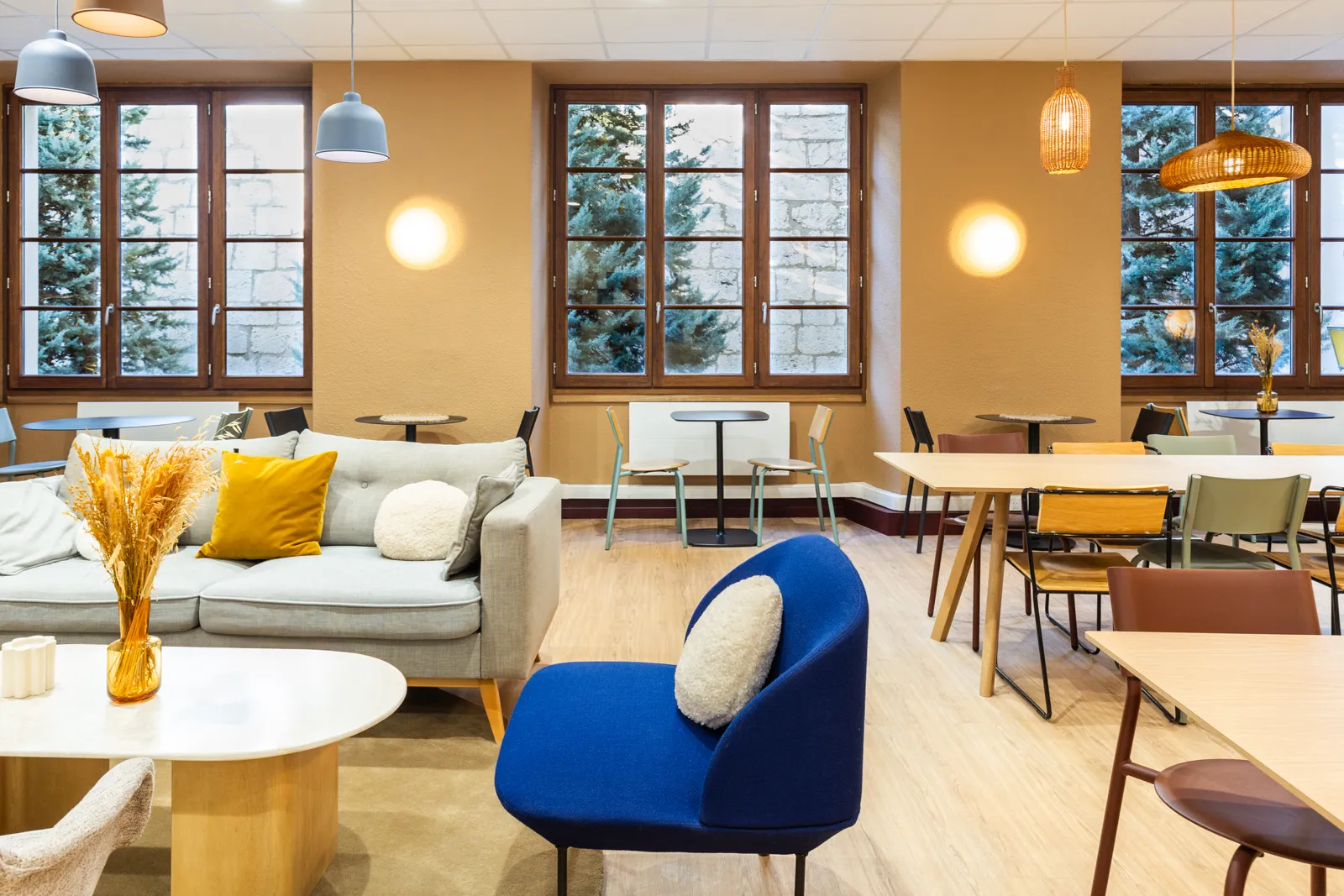 Morning coworking space in Paris, with sofas, a blue armchair and work tables beneath tall windows